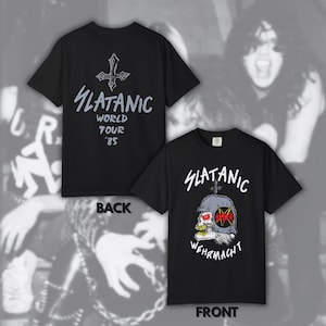 以下が含まれることがあります： 前面と背面が示された黒の半袖Tシャツ。前面にはヘルメットをかぶった頭蓋骨と「SLATANIC WEHRMACHT」の文字が描かれています。背面には逆十字のグラフィックと、グレーの文字で「SLATANIC WORLD TOUR '85」と記されています。