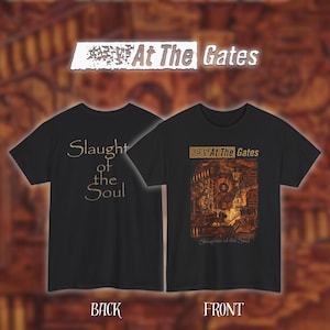 Op de afbeelding: Zwarte t-shirts met de tekst "At The Gates" en "Slaughter of the Soul". Eén shirt toont de achterkant met de tekst "Slaughter of the Soul". Het andere shirt toont een gedetailleerde afbeelding.