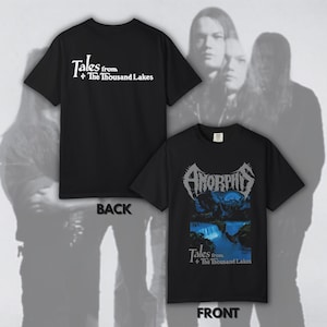May include: Black t-shirts with band graphics. One shirt displays "Tales from + The Thousand Lakes" in white text on the back. The front shirt features "Amorphis" above a blue and black landscape with the same text.