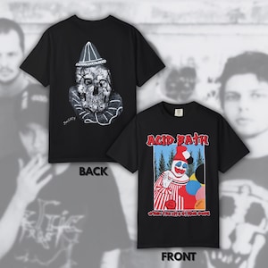 Peut inclure: Un t-shirt noir à manches courtes présenté de face et de dos. Le devant présente un graphique de clown avec des ballons et le texte ACID BATH et WHEN THE KITE STRING POPS. Le dos affiche une illustration en noir et blanc d'un crâne avec un chapeau de clown.