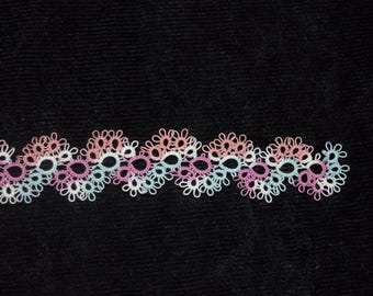 May include: A horizontal strip of tatting lace featuring a repeating wave pattern. The delicate thread work is composed of interconnected loops in alternating shades of soft pink, light blue, white, and lavender, creating a continuous decorative trim.