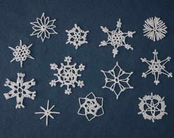 Op de afbeelding: Een verzameling van twaalf witte, gehaakte sneeuwvlokken in diverse ontwerpen. De sneeuwvlokken zijn gerangschikt op een donkerblauwe achtergrond, waarbij hun ingewikkelde patronen en delicate texturen worden getoond. Ideaal voor winterse knutselwerken en decoraties.