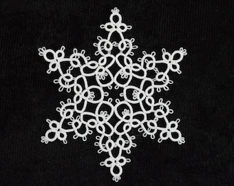 Op de afbeelding: Een wit, ingewikkeld sneeuwvlokontwerp tegen een zwarte achtergrond. De sneeuwvlok is gemaakt van delicate, geluste patronen, waardoor een kantachtig uiterlijk ontstaat. Het ontwerp is symmetrisch, met zes punten die uitstralen vanuit een centrale kern.