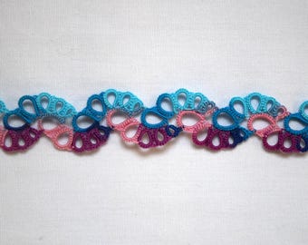 May include: A decorative trim featuring a repeating wave pattern created with tatting lace technique. The lace is composed of interconnected loops in a vibrant gradient of colors, including shades of bright turquoise, light pink, and deep purple.