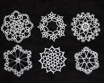 Op de afbeelding: Zes witte, handgemaakte kanten doilies in verschillende sneeuwvlokachtige ontwerpen zijn gerangschikt op een zwarte achtergrond. Elke doily heeft ingewikkelde patronen van lussen en rondingen, die het delicate vakmanschap laten zien.