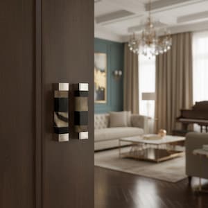 Puede incluir: Un par de manijas de puerta decorativas con un diseño rectangular. Las manijas presentan secciones alternas de plata, negro y materiales estampados, montadas en una puerta de madera marrón oscuro. El fondo muestra una sala de estar lujosa.