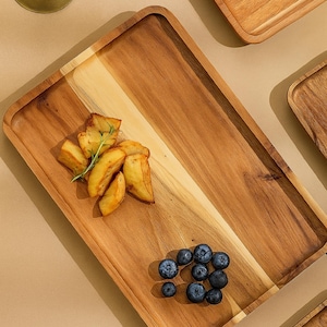 May include: Wooden serving trays with a rectangular shape and rounded corners. One tray is filled with fried potato wedges and blueberries. The trays are made of light and dark wood tones.