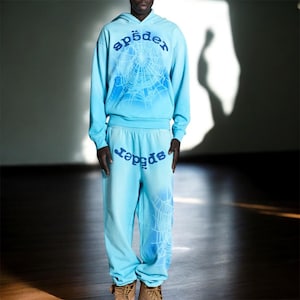 Puede incluir: Conjunto de sudadera con capucha y pantalón de chándal azul claro. La sudadera con capucha presenta un diseño de telaraña y la palabra "sp5der" en azul. El pantalón de chándal también tiene la palabra "sp5der" y un diseño de telaraña.