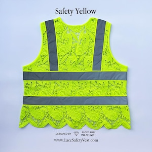 Op de afbeelding: Een veiligheidsvest van felgeel kant met grijze reflecterende strepen en accenten. Het vest heeft een geschulpte onderrand en de tekst "Safety Yellow" bovenaan. Het ontwerp bevat de tekst "Designed by Floyd Ruby" en een websiteadres.