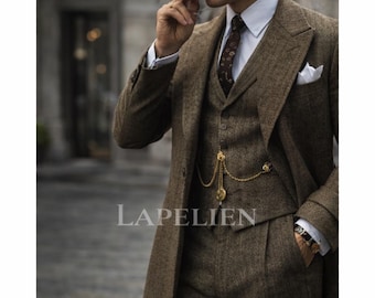 May include: A three-piece brown tweed suit with a long coat, vest, and trousers. The suit features a white pocket square, a patterned tie, and a gold pocket watch chain. The image includes the text "LAPELIEN".