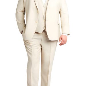 Könnte beinhalten: Ein dreiteiliger Anzug in hellem Beige. Der Anzug besteht aus einem Blazer, einer Weste und einer Hose. Der Blazer hat zwei Knöpfe und ein fallendes Revers. Die Weste hat einen Knopfverschluss. Die Hose ist gerade geschnitten. Braune Lederschuhe vervollständigen den Look.