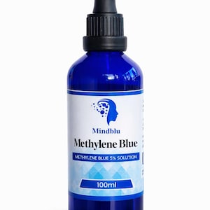 Może przedstawiać: Butelka z ciemnoniebieskiego szkła z czarnym zakraplaczem. Etykieta zawiera napis "Mindblu Błękit Metylenowy 5% Roztwór" i "100ml". Butelka ma białą etykietę z niebieskim geometrycznym wzorem.