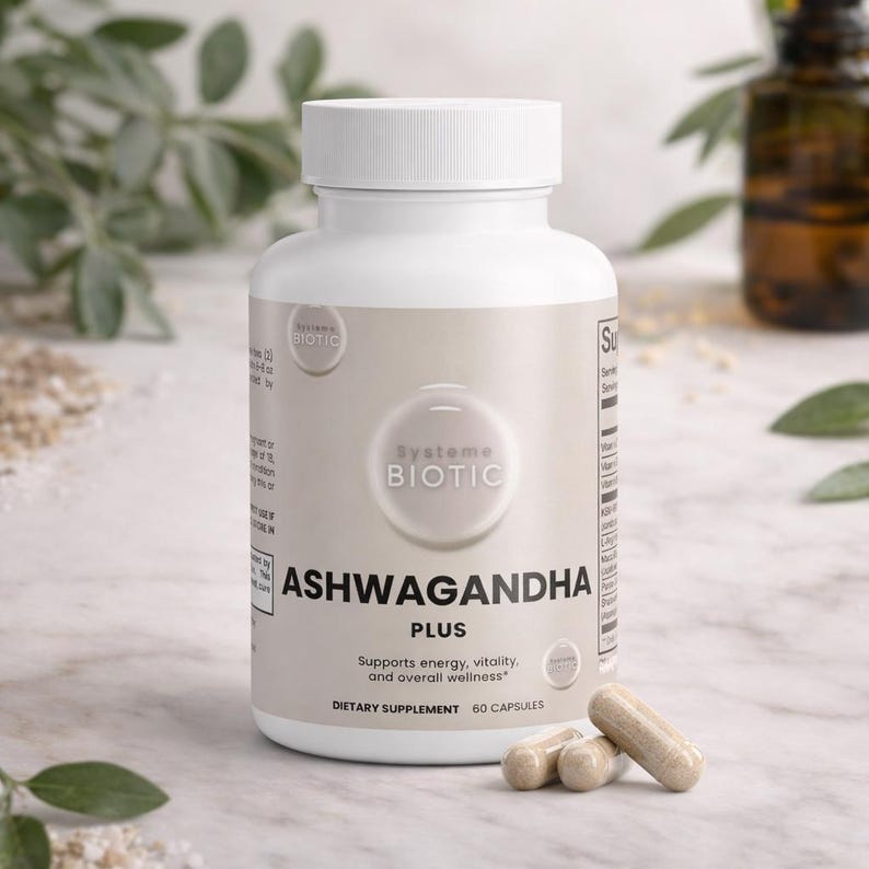 May include: A white bottle of Ashwagandha Plus dietary supplement with a white cap. The label includes the text "Systeme Biotic" and "Supports energy, vitality, and overall wellness." Three capsules are in front of the bottle.