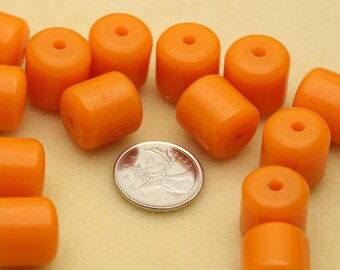 May include: A collection of smooth, cylindrical orange beads with a central hole, arranged around a Canadian 25-cent coin for scale. The beads have a solid, opaque finish and a uniform shape, providing a clear visual reference for their size.