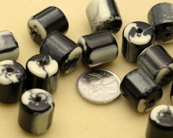 May include: A collection of cylindrical beads featuring a marbled black and white pattern. Each bead has a central hole. A Canadian 25-cent coin is placed among the beads to provide a visual reference for the size of the individual pieces.