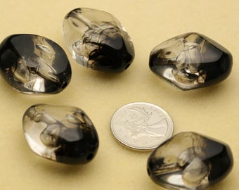 May include: Five translucent, smoke-colored glass beads with irregular, rounded shapes and internal dark swirls. A silver-colored Canadian 25-cent coin is placed in the center for scale, showing a diameter of approximately 0.94 inches.