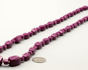 May include: A long necklace featuring a series of smooth, deep purple beads in varying rectangular and square shapes. The beads are strung together in a single strand, and a silver-colored US quarter coin is placed nearby for scale reference.