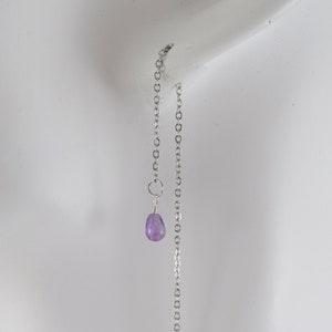 May include: A pair of silver dangle earrings with a small purple gemstone at the end of each chain.