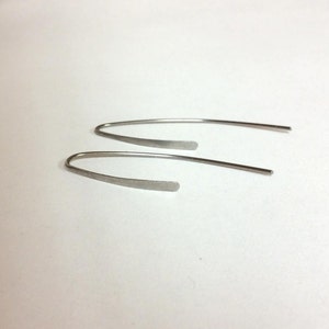 Pu&ograve; includere: Un paio di orecchini d'argento con un design semplice e curvo.