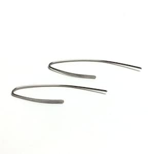 Pu&ograve; includere: Un paio di orecchini a cerchio d'argento con un design semplice e curvo.