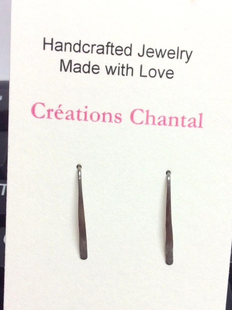 Pu&ograve; includere: Un paio di orecchini d'argento con un design semplice e dritto. Gli orecchini sono esposti su una carta bianca con il testo "Handcrafted Jewelry Made with Love Cr&eacute;ations Chantal".