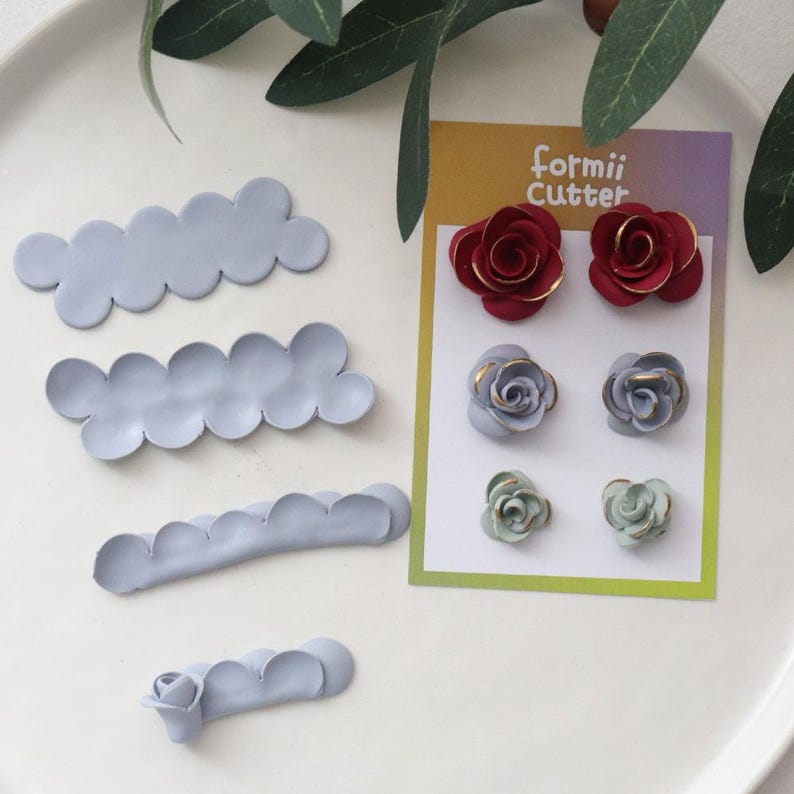 May include: Clay flower cutters and finished clay flowers in red, blue, and green. The cutters are in a cloud shape. The finished flowers are on a card that says "formii Cutter".