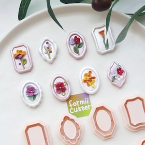 May include: A collection of floral-themed wax seals in various shapes and colors, including pink, white, and gold. The seals feature detailed flower designs. Also included are several pink and peach-colored cutters with the text "formii Cutter".