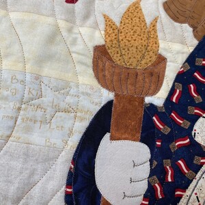 May include: A quilted fabric wall hanging with a blue and red patterned fabric, a brown torch, and the text "Be a Kid, Smile Free, Let Happiness Begin, Let You Be You".