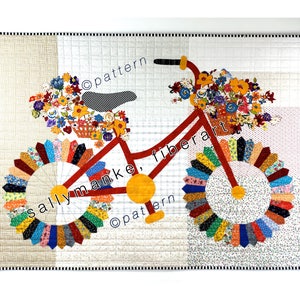 May include: A red bicycle with yellow wheels and a basket of flowers on the handlebars. The bicycle is made of fabric and is a quilt pattern. The quilt is surrounded by a white border with a black and white checkered pattern.