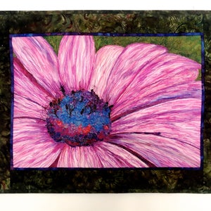 May include: A close-up of a pink flower with a blue and purple centre. The flower is surrounded by a dark green frame.