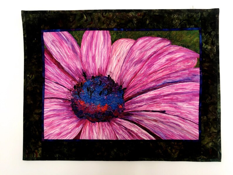 May include: A close-up of a pink flower with a dark purple centre. The flower is surrounded by a dark green frame.