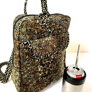 May include: A black and gold patterned backpack with a top handle and adjustable straps. The backpack has a zipped pocket on the front. A silver can cooler with a black lid and a straw is next to the backpack.