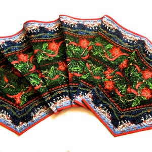 Könnte beinhalten: Ein sechseckiger Weihnachtstischläufer mit einem grünen, roten und blauen Design mit Weihnachtssternen, Stechpalmen und Bändern. Der Läufer ist gesteppt und hat einen gewellten Rand.