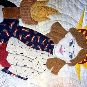 May include: A quilted fabric artwork depicting the Statue of Liberty. The figure is made of various fabric scraps, including red, white, blue, and brown. The Statue of Liberty is holding a torch in her right hand and has a crown on her head.