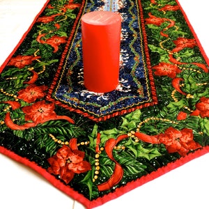 Könnte beinhalten: Ein roter und grüner Weihnachtstischläufer mit einer roten Kerze in der Mitte. Der Läufer zeigt ein Poinsettien-Design mit Stechpalmenblättern und roten Bändern.