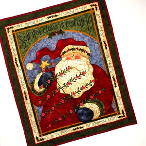 Exquisitely quilted vintage advent calendar featuring Santa Claus holding a Christmas Tree. Twenty-four buttons have been securely stitched to hang the cotton and felt ornaments day each day leading up to Christmas. Nancy Halverson holiday panel.