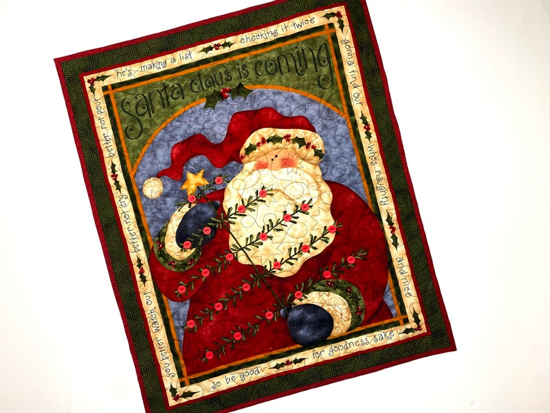 Exquisitely quilted vintage advent calendar featuring Santa Claus holding a Christmas Tree. Twenty-four buttons have been securely stitched to hang the cotton and felt ornaments day each day leading up to Christmas. Nancy Halverson holiday panel.