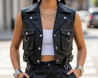 Può includere: Un gilet in pelle nera con dettagli argentati, tra cui bottoni, fibbie e anelli a D. Il gilet ha due tasche frontali ed è abbinato a pantaloni in pelle nera. L'outfit è impreziosito da collane d'oro a strati, bracciali d'argento e orecchini pendenti lunghi.