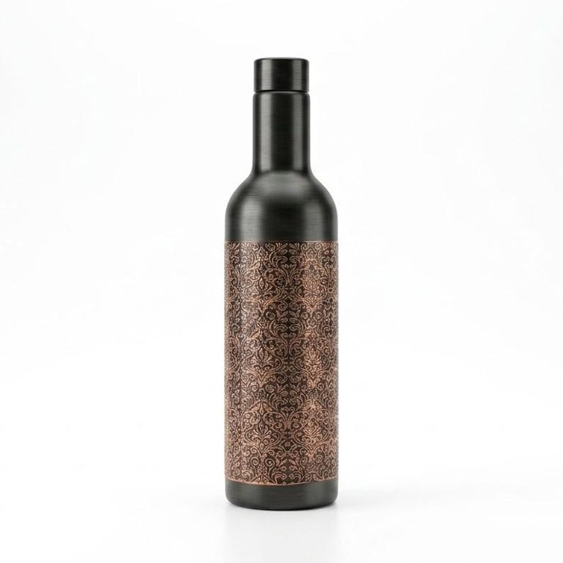 Front view of a 1000ml engraved copper water bottle featuring a sophisticated matte black exterior and ornate antique copper detailing. The tall bottle has a traditional Indian inspired decorative pattern and elegant vintage appearance. Ideal for everyday drinking water, yoga sessions, wellness routines, travel and as a stylish reusable bottle.