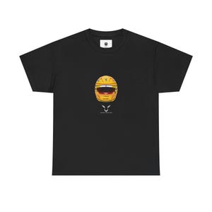 以下が含まれることがあります： 黄色いレーシングヘルメットのデザインが施された黒いTシャツ。ヘルメットには赤と黄色のアクセントがあり、下に「LEWIS HAMILTON」の文字があります。シャツの上部には小さな白いアスタリスクがあります。