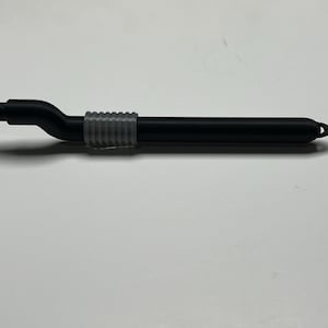 Puede incluir: Un lápiz óptico negro con punta y agarre grises. El lápiz óptico tiene un diseño curvo cerca de la punta y un lazo en el extremo. El lápiz óptico está diseñado para su uso con dispositivos de pantalla táctil.