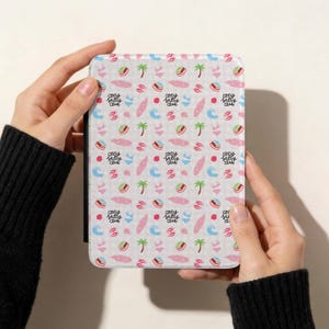 Puede incluir: Una funda blanca para tableta con un patrón repetido de ilustraciones rosas y azules con temática playera, que incluye palmeras, tablas de surf y tops de bikini. El texto "cozy salty club" también se repite.