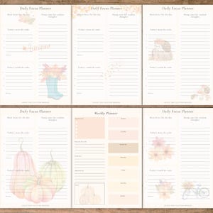 May include: A selection of open Daily Focus Planners and a Weekly Planner. The planners feature watercolour illustrations of autumn themes, including pumpkins, flowers, and a bicycle. Each planner has lined sections for notes and tasks.