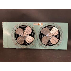May include: A vintage, rectangular, light-blue industrial fan unit with two circular fan cages. Each cage has a metal fan with four blades. The unit has a metal casing and a small, round access port.