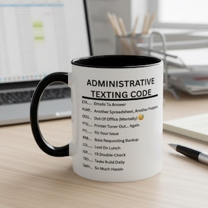 Può includere: Tazza in ceramica bianca con manico e bordo neri. La tazza presenta il testo "ADMINISTRATIVE TEXTING CODE" e un elenco di acronimi relativi al lavoro. La tazza è su una superficie di legno.