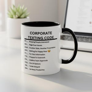 Pode incluir: Uma caneca de cerâmica branca com interior e alça pretos. A caneca apresenta o texto "CORPORATE TEXTING CODE" e vários acrónimos com os seus significados, como "KPI... Keeping People Interested" e "WPH... Waiting For Happy Hour". Uma pequena planta num vaso branco está no fundo.