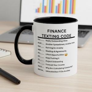 Könnte beinhalten: Weißer Keramikbecher mit schwarzem Innenraum und Griff. Der Becher zeigt den Text "FINANCE TEXTING CODE" mit einer Liste von Finanz-Akronymen und ihren Bedeutungen. Ein humorvolles Geschenk für Finanzexperten.