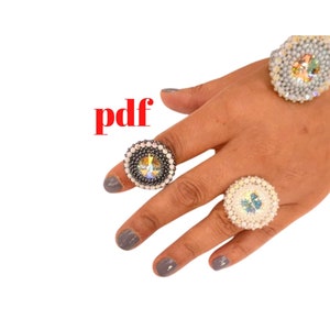 May include: Three beaded rings with crystal accents. The rings are white, black, and gray.