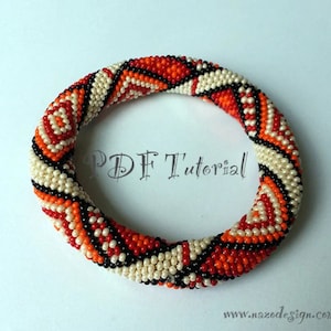 May include: A beaded bracelet featuring a geometric pattern in black, white, orange, and red. The bracelet is crafted with small seed beads and has a spiral design.