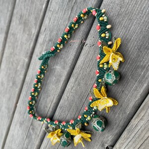 May include: A green, red, and yellow beaded necklace with crocheted flower charms and green and silver beads.